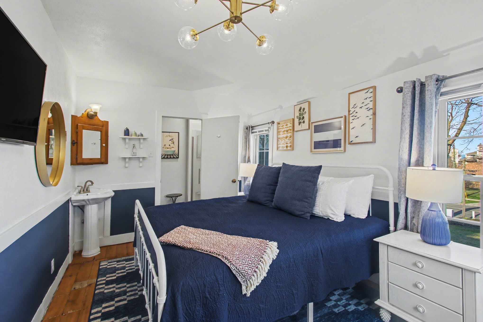 king bed, blue rug, sink and bathroom