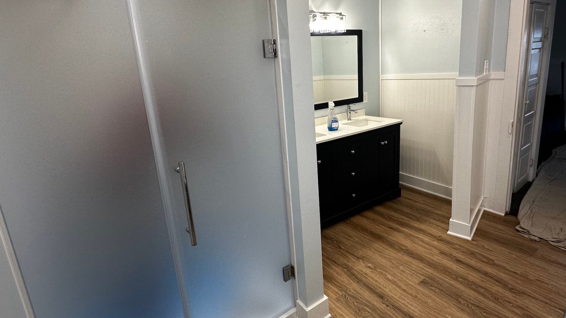 A modern bathroom featuring a black vanity, mirror, and frosted glass shower door. A modern bathroom featuring a black vanity, mirror, and frosted glass shower door.