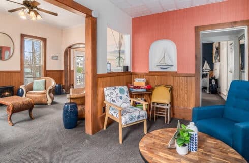 A cozy living room with wooden accents, a blue chair, patterned seating, and nautical decor.