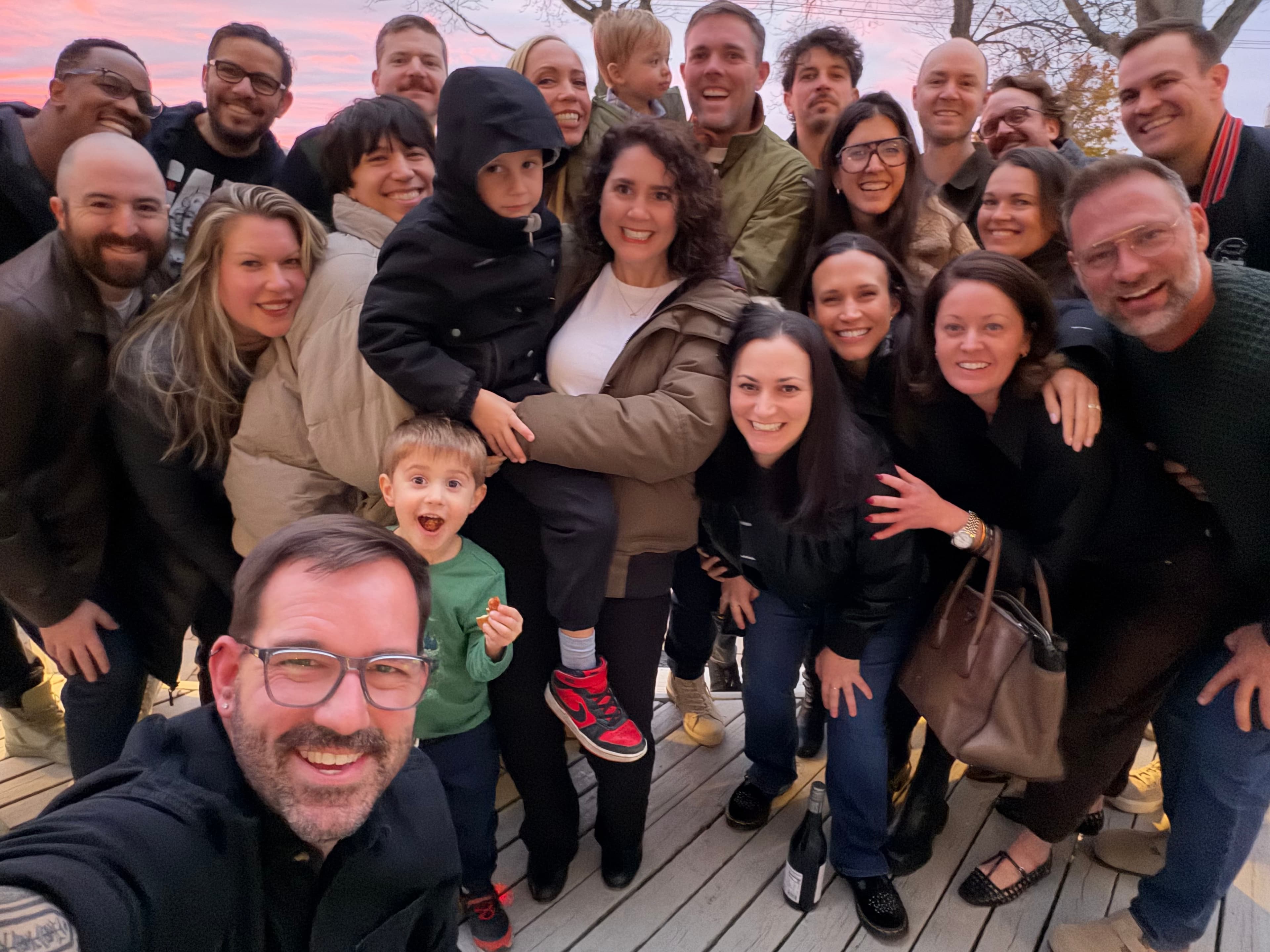 A large group of smiling people posing together outdoors at sunset. A large group of smiling people posing together outdoors at sunset.