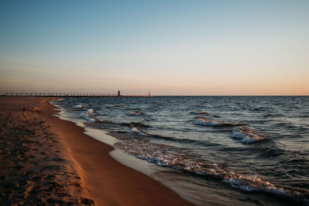 A serene beach at sunset with gentle waves lapping at the shore and a distant pier. A serene beach at sunset with gentle waves lapping at the shore and a distant pier.