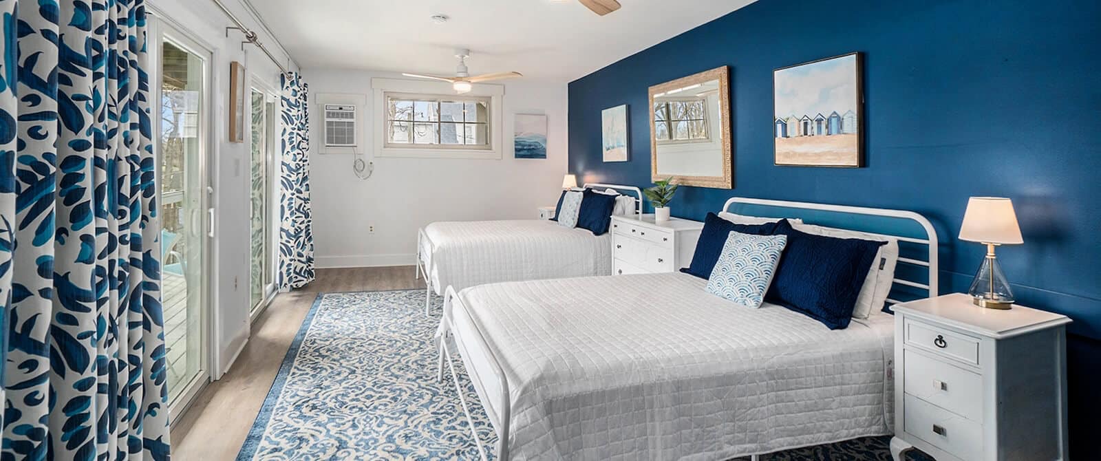Bright bedroom with two twin beds, blue accent wall, and coastal decor.
