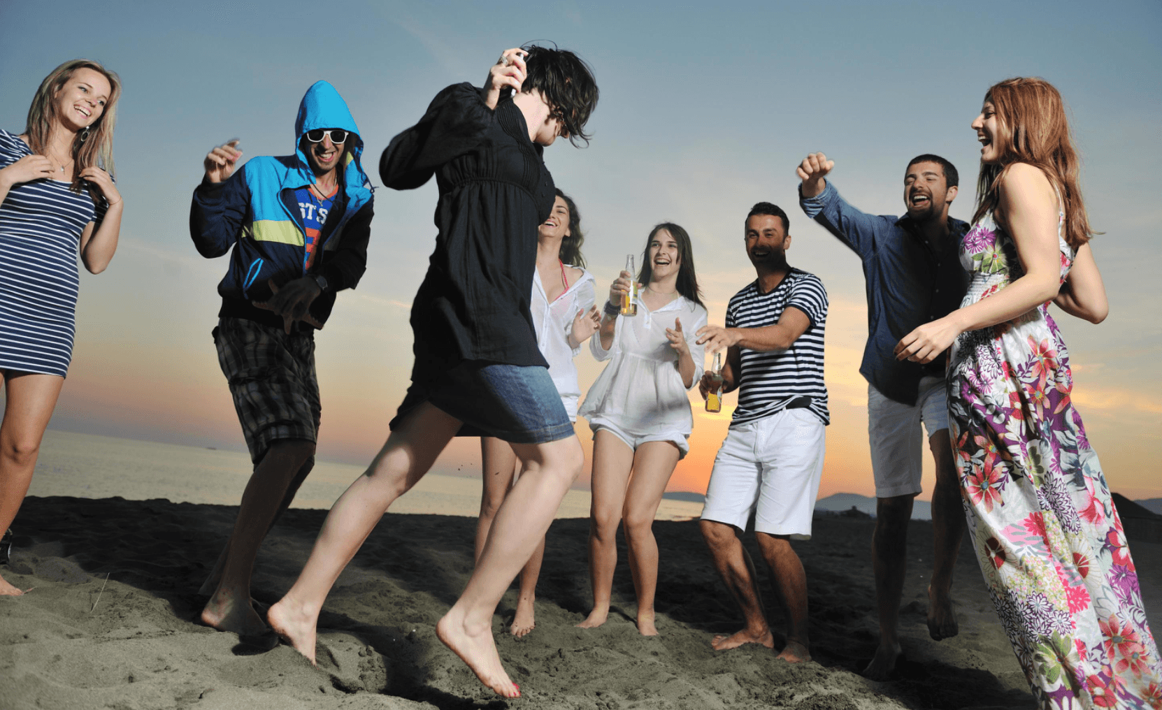 A group of people joyfully dancing on the beach at sunset. A group of people joyfully dancing on the beach at sunset.