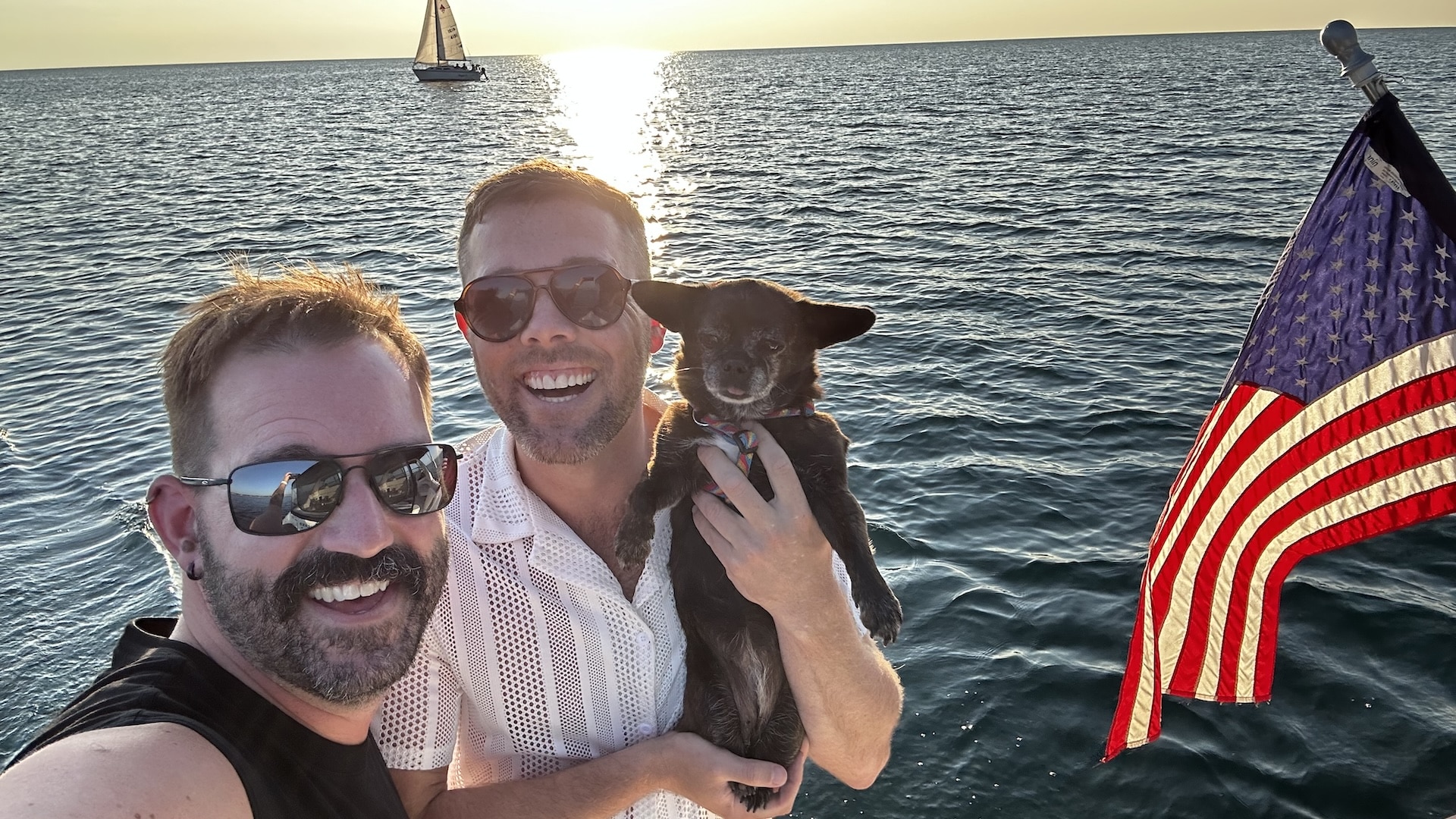 two men holding a small dog on a boat on Lake Michigan