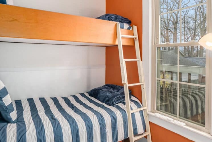 A bedroom with twin bunk beds with blue and white striped bedding and a ladder to the top bunk.