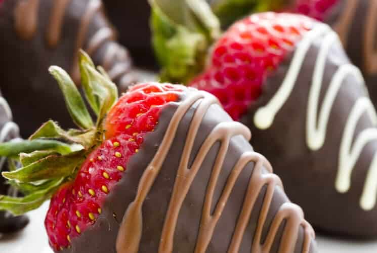 Two chocolate covered strawberries, drizzled with brown and white chocolate.